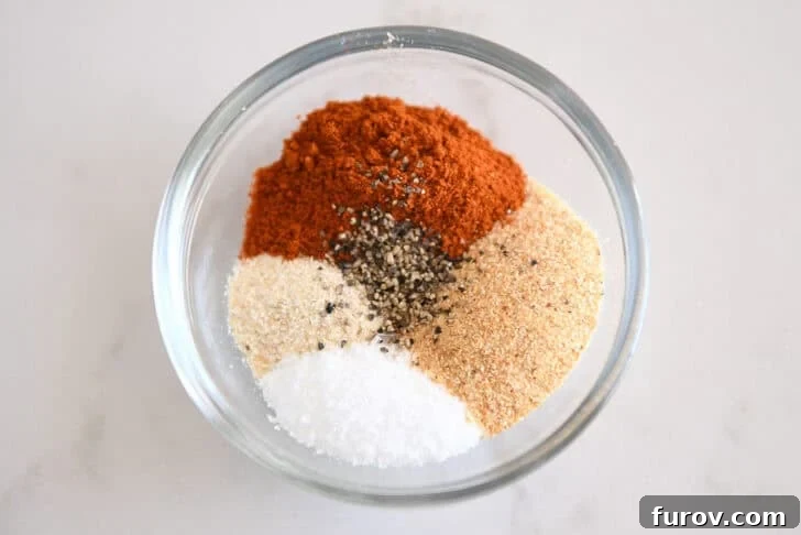 Glass bowl with smoked paprika, onion powder, garlic powder, salt and pepper.
