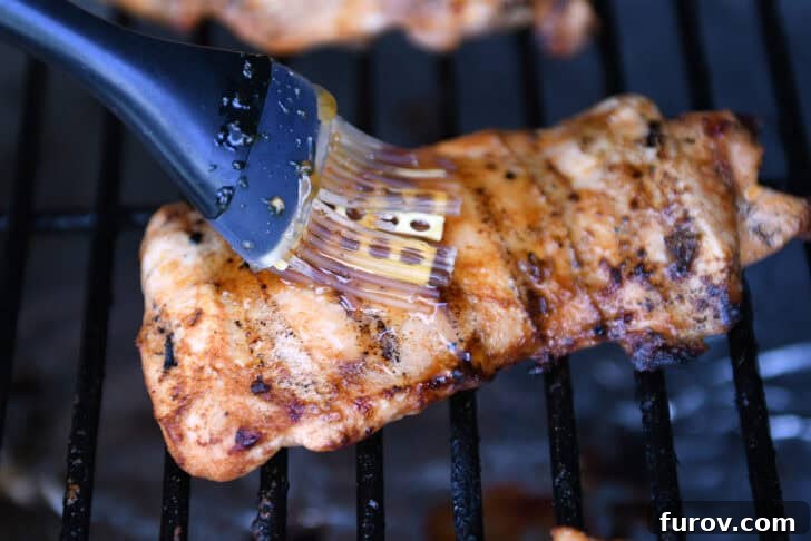 Brushing honey garlic sauce on grilled chicken.