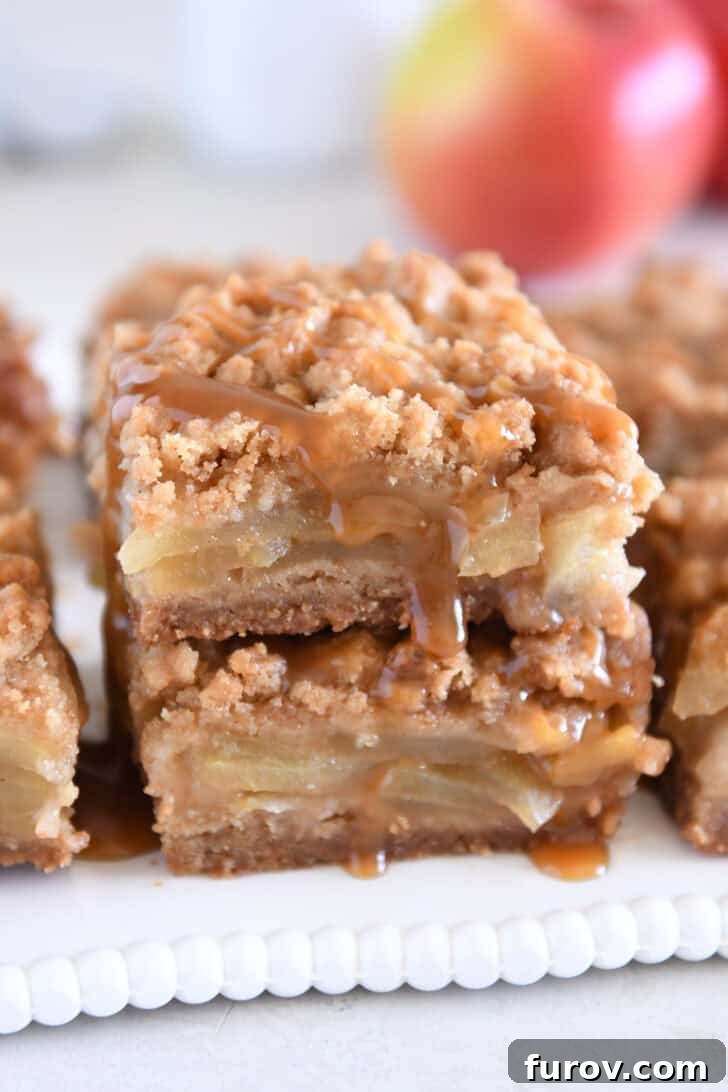 Two caramel apple crumble bars stacked on white tray.