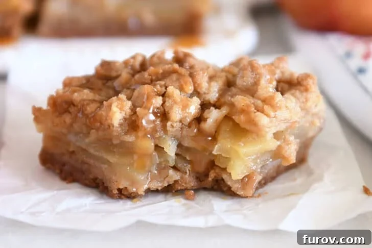 One caramel apple crumble bar on white parchment paper with bite taken out.