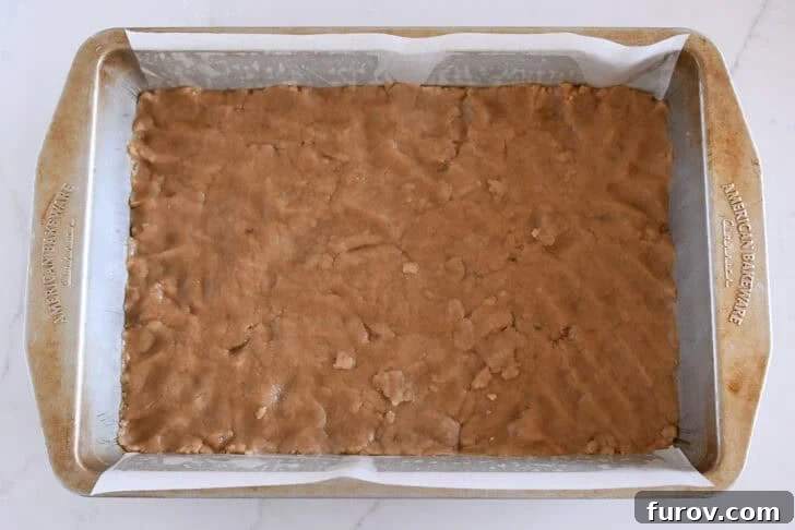 Metal 9X13-inch pan with parchment and unbaked crust pressed into the bottom.