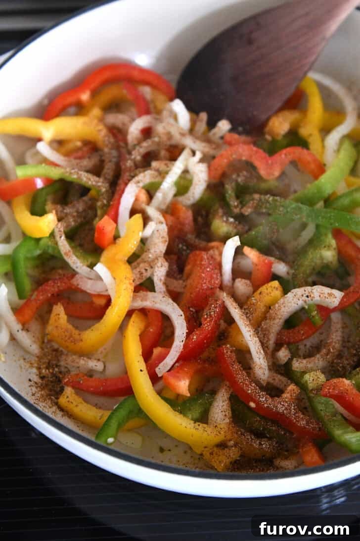 Sizzling Chicken Fajitas with Peppers and Onions 5 White cast iron skillet with sliced onions, bell peppers and fajita seasonings.
