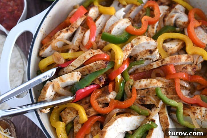 Sizzling Chicken Fajitas with Peppers and Onions 7 White cast iron skillet filled with sliced fajita chicken breasts, bell peppers and onions.