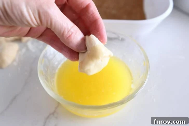 Fluffy Cinnamon Roll Bites Recipe: Soft, Bite-Sized Treats 6 Dipping small piece of roll dough in melted butter.