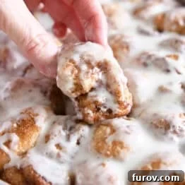 Fluffy Cinnamon Roll Bites Recipe: Soft, Bite-Sized Treats 10 Lifting fluffy cinnamon roll bite out of pan of cinnamon roll bites.