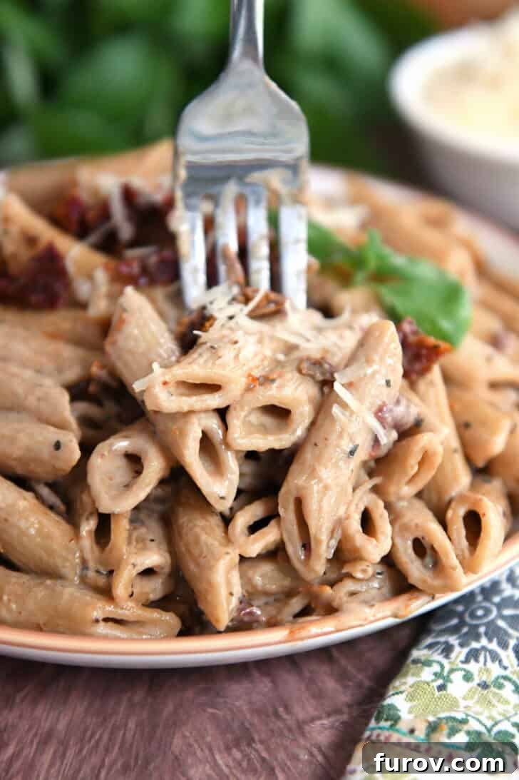 Brown rimmed plate with cooked Instant Pot marry me pasta with sun-dried tomatoes on top with fresh basil.