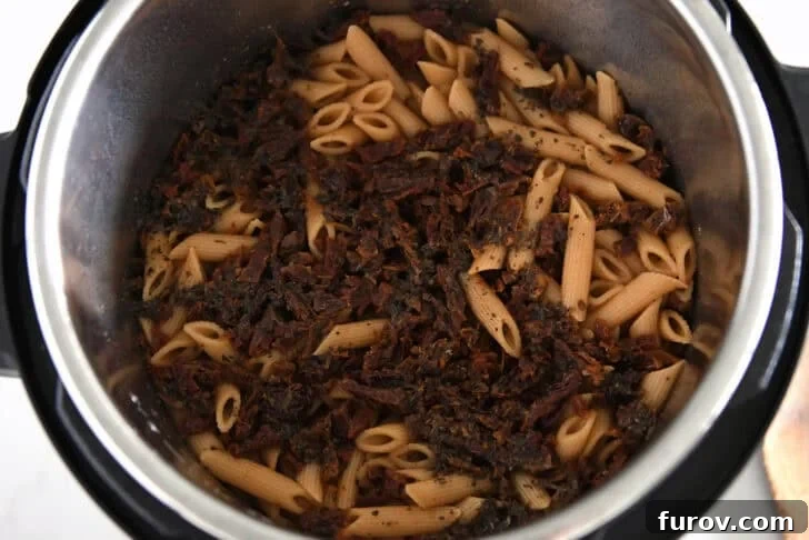 Instant pot with cooked pasta and sun-dried tomatoes.