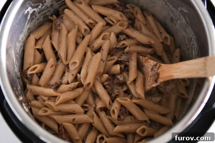 Cooked, creamy pasta in Instant Pot with sun-dried tomatoes.