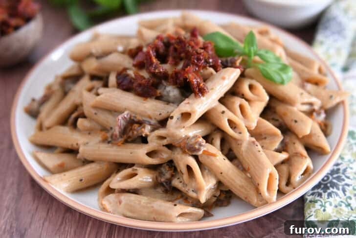 Brown rimmed plate with cooked Instant Pot marry me pasta with sun-dried tomatoes on top with fresh basil.