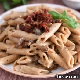 Brown rimmed plate with cooked Instant Pot marry me pasta with sun-dried tomatoes on top with fresh basil.
